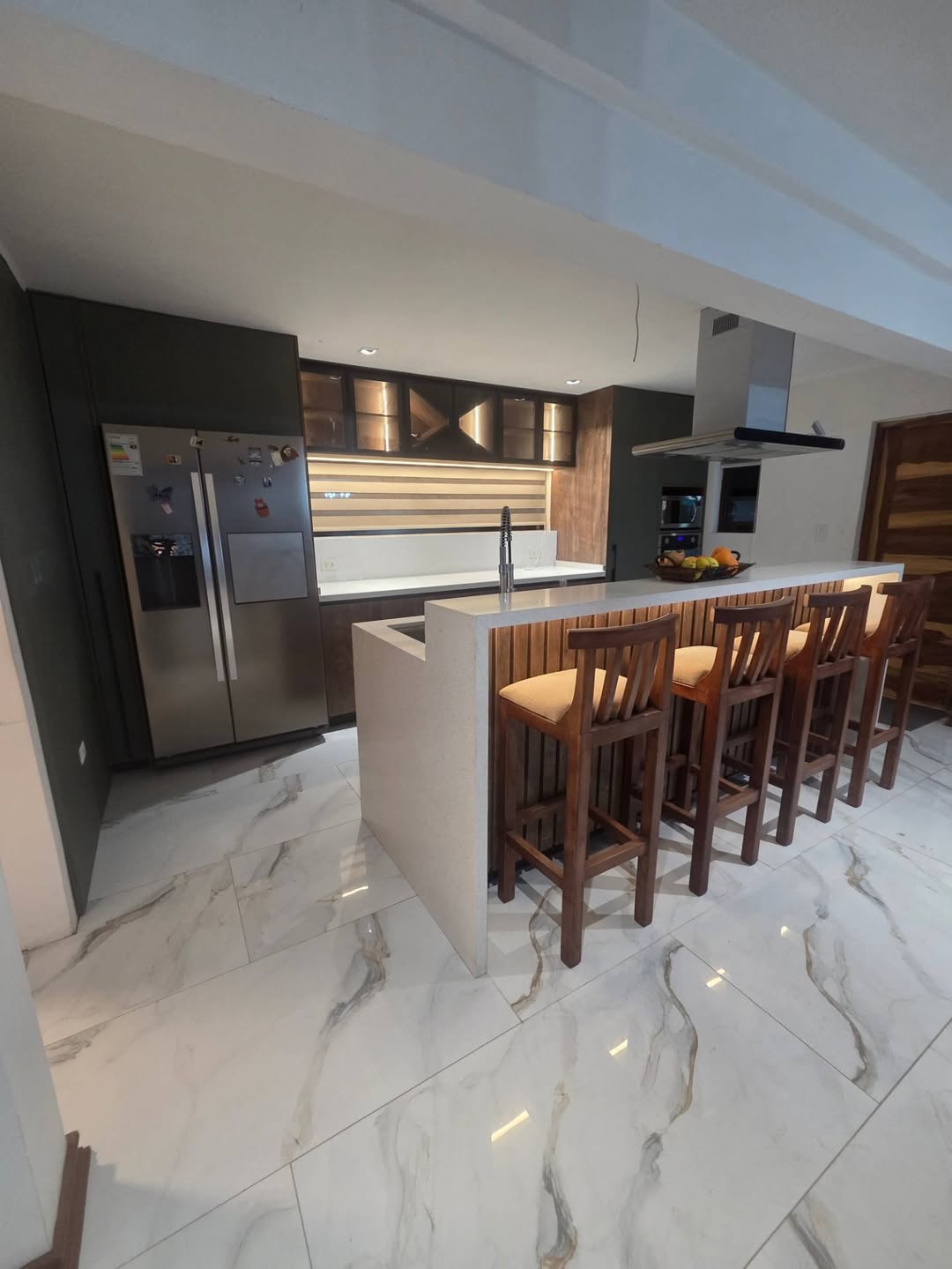 Cocina con muebles oscuros, terminaciones de madera e isla con cubierta clara, publicada por Muebles More